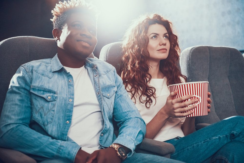 رجل يجلس في السينما مع زوجته.. تعبيرية عن أفكار هدايا عيد الزواج الأول