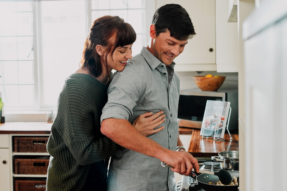 زوج يساعد زوجته في الطهي.. تعبيرية عن ماهي أقوى علامات الحب عند الرجل؟