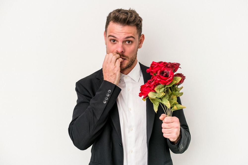 رجل متوتر ويمسك بباقة من الورود.. تعبيرية عن علامات الحب عند الرجل العصبي 