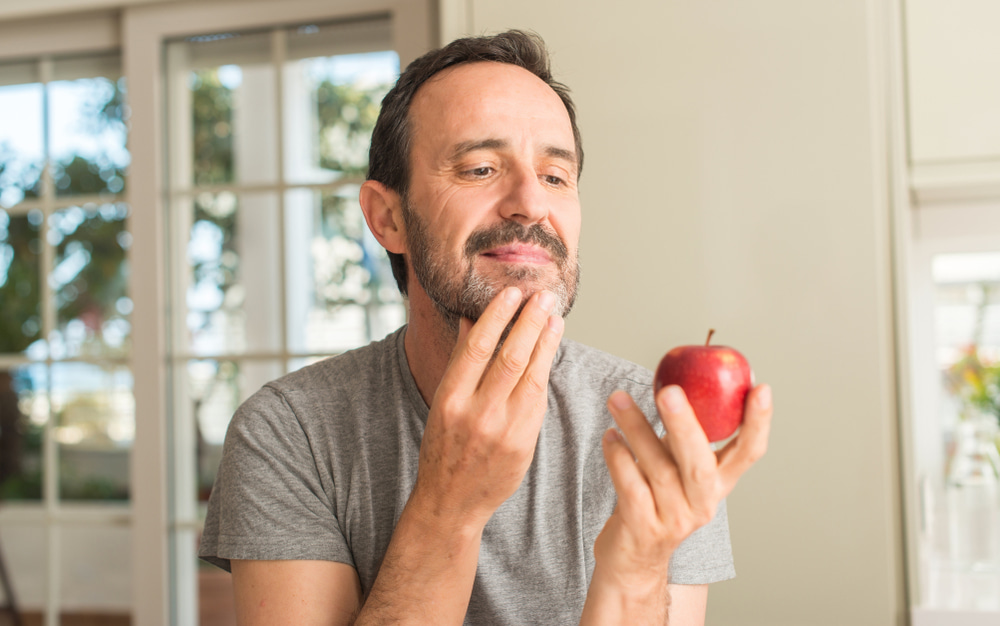 رجل ينظر إلى التفاح الأحمر.. تعبيرية عن ما هي فوائد التفاح الأحمر 