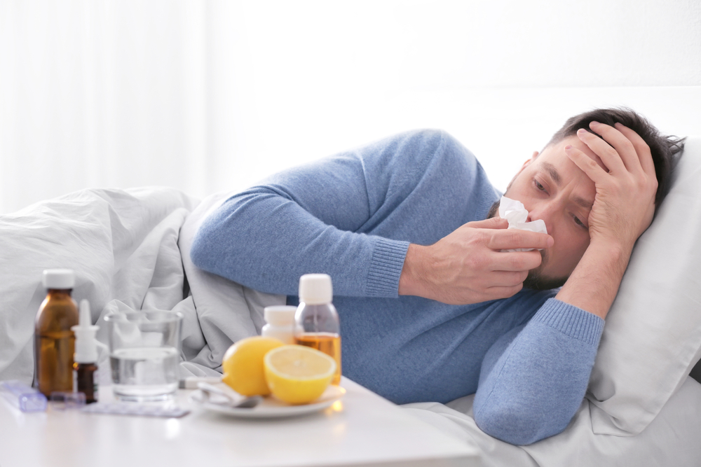 رجل يرقد على السرير ممسكا بأنفه ورأسه ويحتاج إلى فوائد الفلفل الحار لعلاج نزلات البرد 