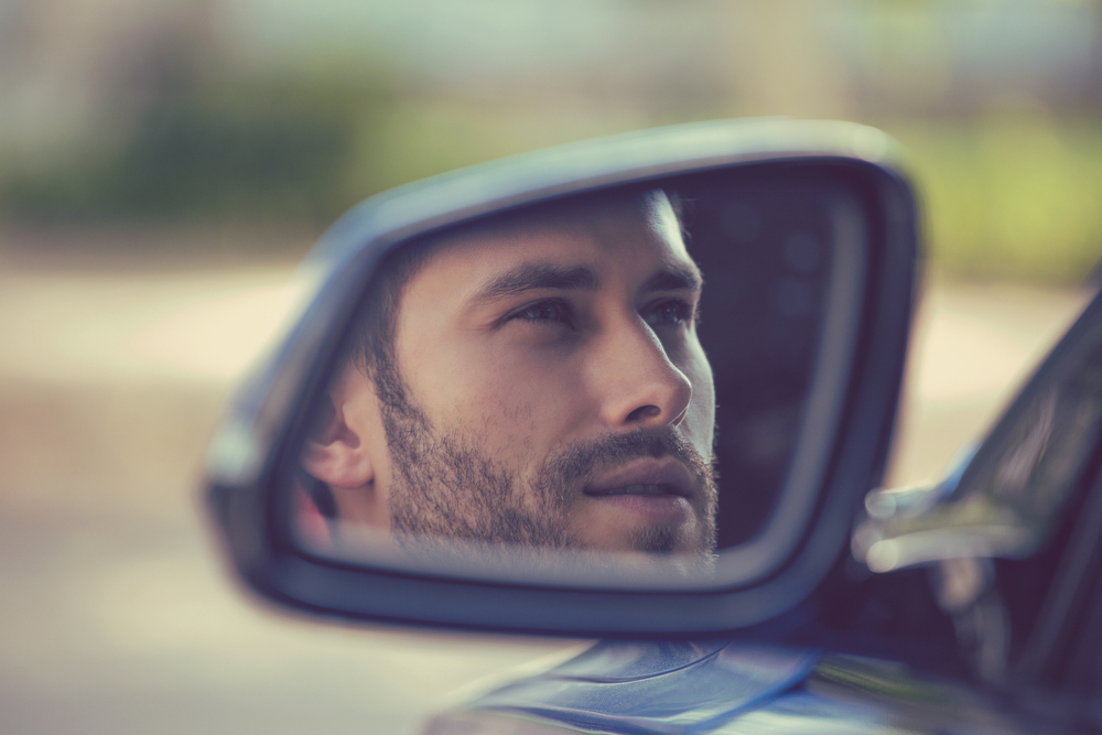 رجل يظهر في مرآة سيارته